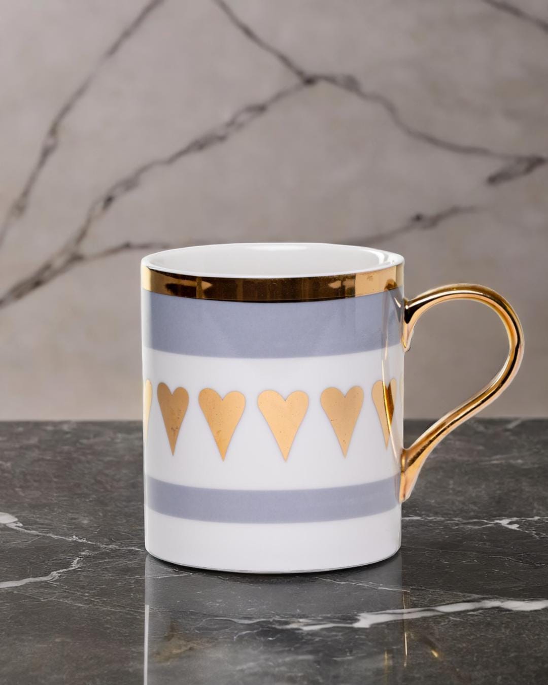 Ceramic mug adorned with golden hearts and a golden handle.