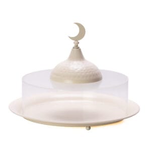 Round cream metal serving platter with a clear acrylic dome cover featuring a hammered gold-tone handle topped with a crescent moon.