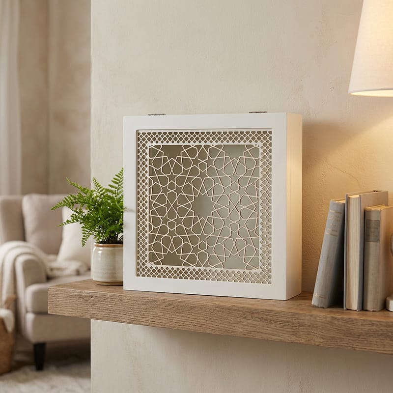 White square box featuring detailed arabesque star and lattice pattern, placed on marble table beside small succulent in modern living room